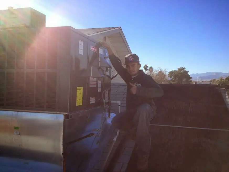 HVAC technician performing AC Tune-Up on a rooftop unit in Lowell